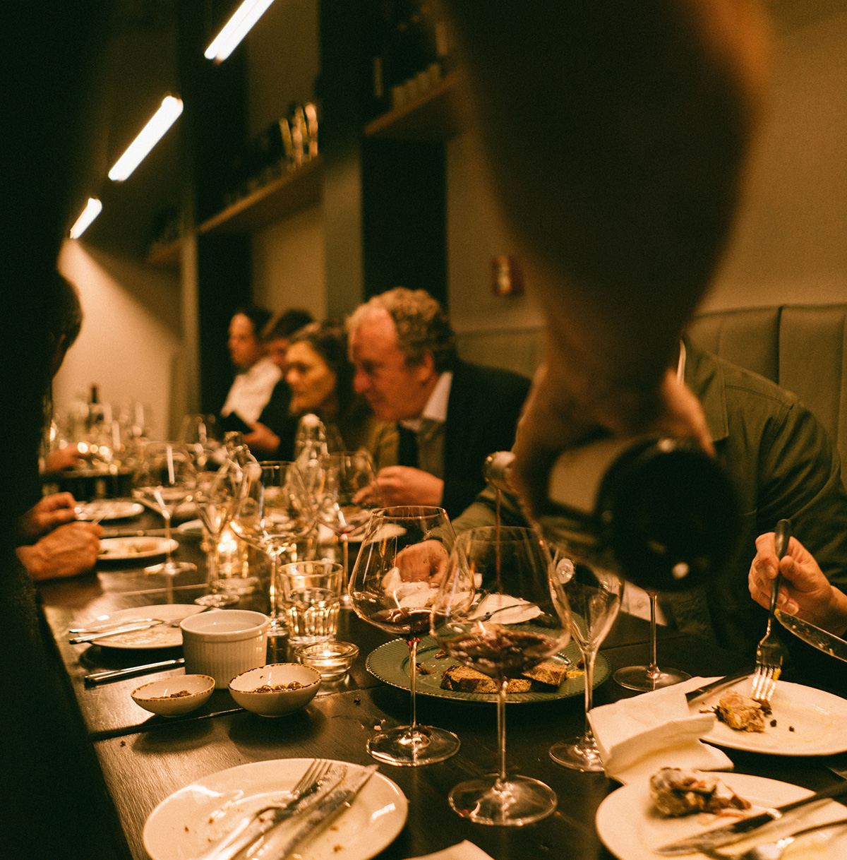 Michael Henley pouring a bottle of wine to a table happy diners